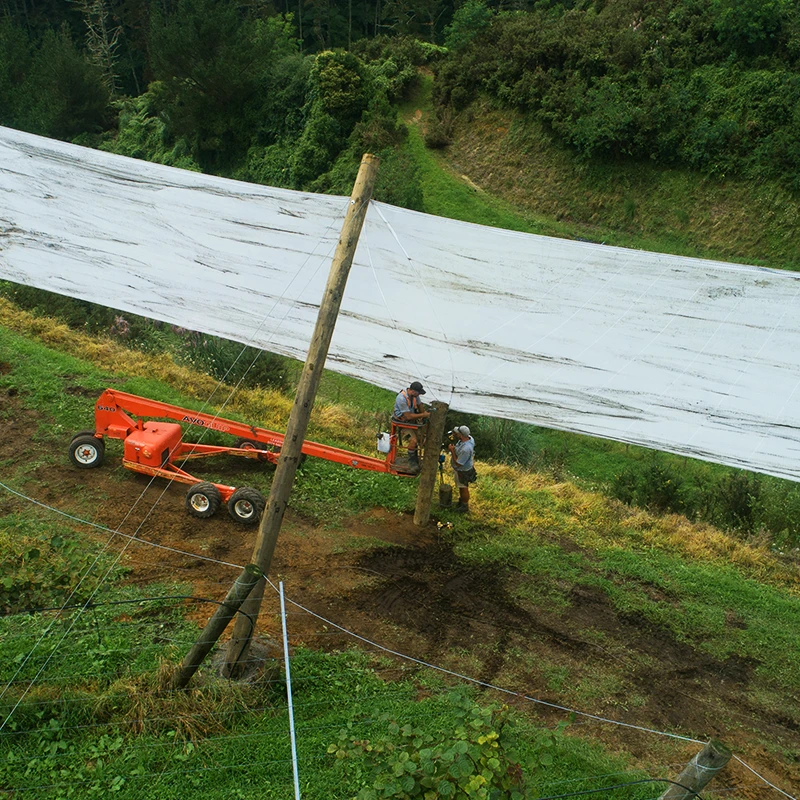 Aerial image looking down on a worker securing shelter cloth in place against rammed timber beam